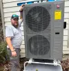 man stands beside large outdoor rheem hvac unit near a house