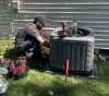 Technician fixing an HVAC outside of a house.