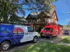 One blue and white van and a red van in the driveway of a house. 