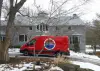 A red Empire Heating & Air Conditioning van in the driveway of a house with snow on the ground.