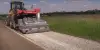 A tractor paving the side of a road.