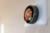 A smart thermostat on a wall displays the temperature set to 74 degrees.