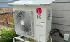 Outdoor LG Smart Inverter air conditioning unit installed next to a house with a gray wall.