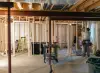 Two people work on framing and construction inside a house under renovation.