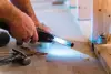 A person uses a power tool to cut a metal pipe on a construction site floor.