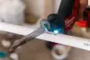 A reciprocating saw cutting through a white PVC pipe.