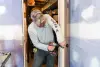 Person installing a doorknob with a drill in a room under construction or renovation.