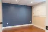 Empty room with blue accent wall, wood floor, white ceiling, and cabinets on the right wall.