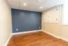 Empty room with wood flooring, blue accent wall, beige walls, and white ceiling with lights.