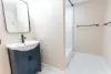 Small bathroom with a dark vanity, mirror, walk-in shower, and hexagonal tile floor.