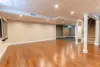 Spacious finished basement with hardwood floors, beige walls, and stairs leading upstairs.