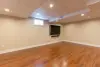 Spacious finished basement with wood flooring, beige walls, recessed lights, and a wall-mounted TV.
