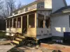 A house with a partially built wooden porch addition under construction in daylight.