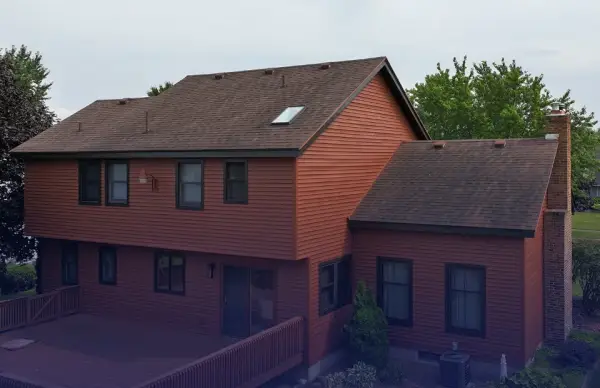 A brown house with new roofing and siding.